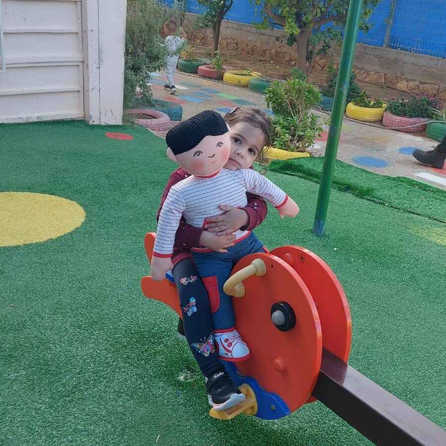 ילדה בגן עם בובה בפיג'מה על נדנדה